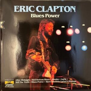 Używane winyle, Płyty winylowe na sprzedaż, sklep winyle online Okładka albumu Erica Claptona „Blues Power EX”, dostępna w sklepie winylowym, przedstawia Claptona na gitarze w świetle jaskrawych świateł scenicznych. Utwory obejmują „After Midnight” i „Layla”. Odwiedź płyty winylowe sklep, aby kupić winyle online już dziś. Sklep online z winylami